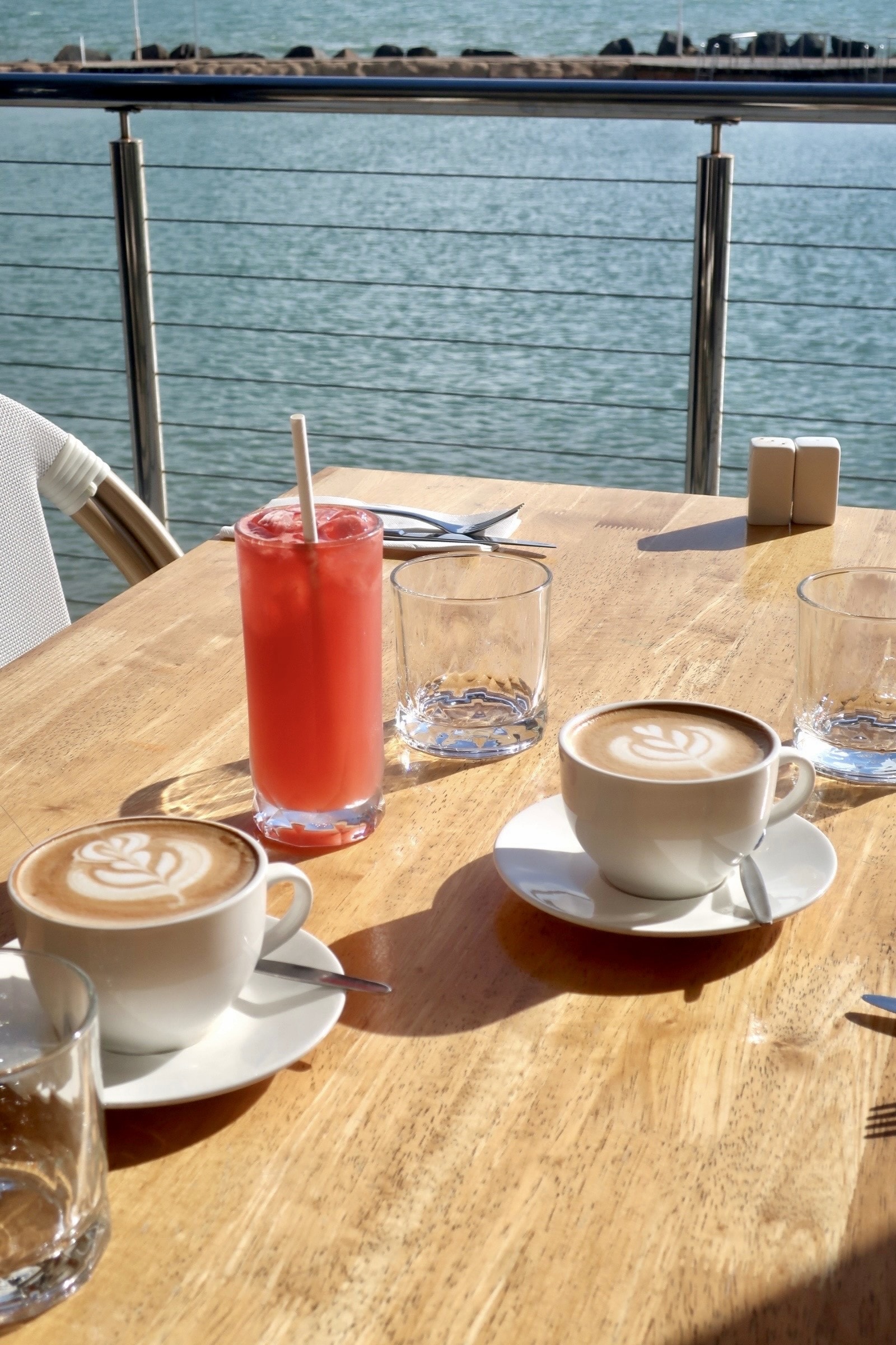 Lattes and a red drink on the waterfront table