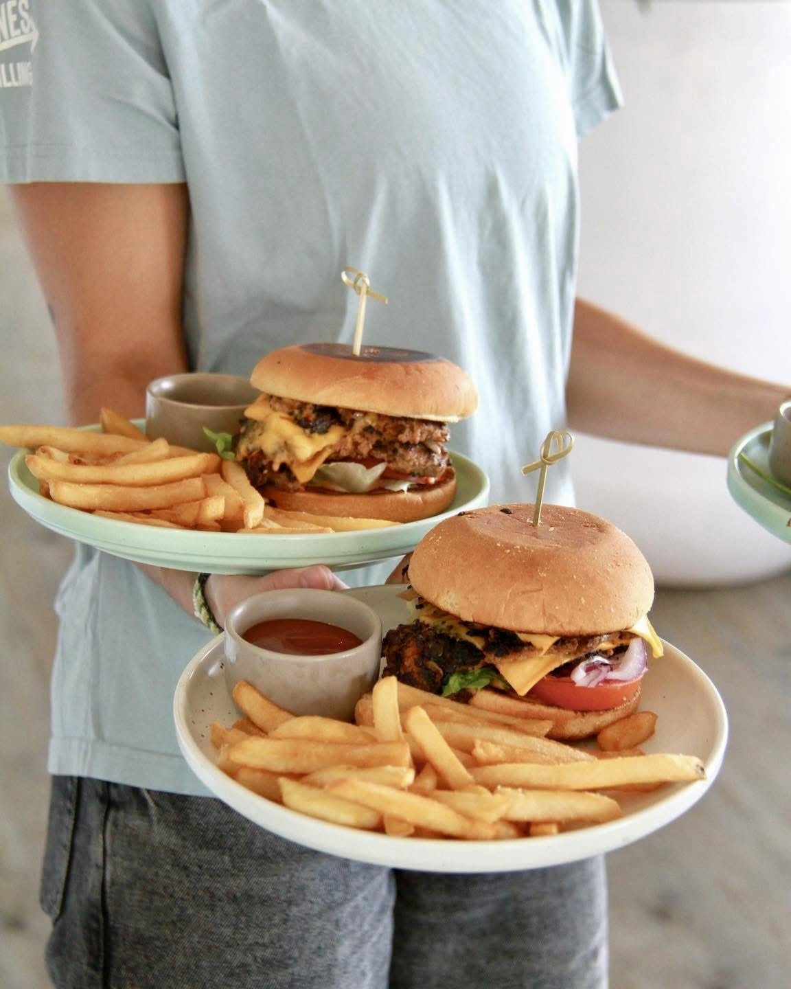 Server carrying two burgers and fries to the table