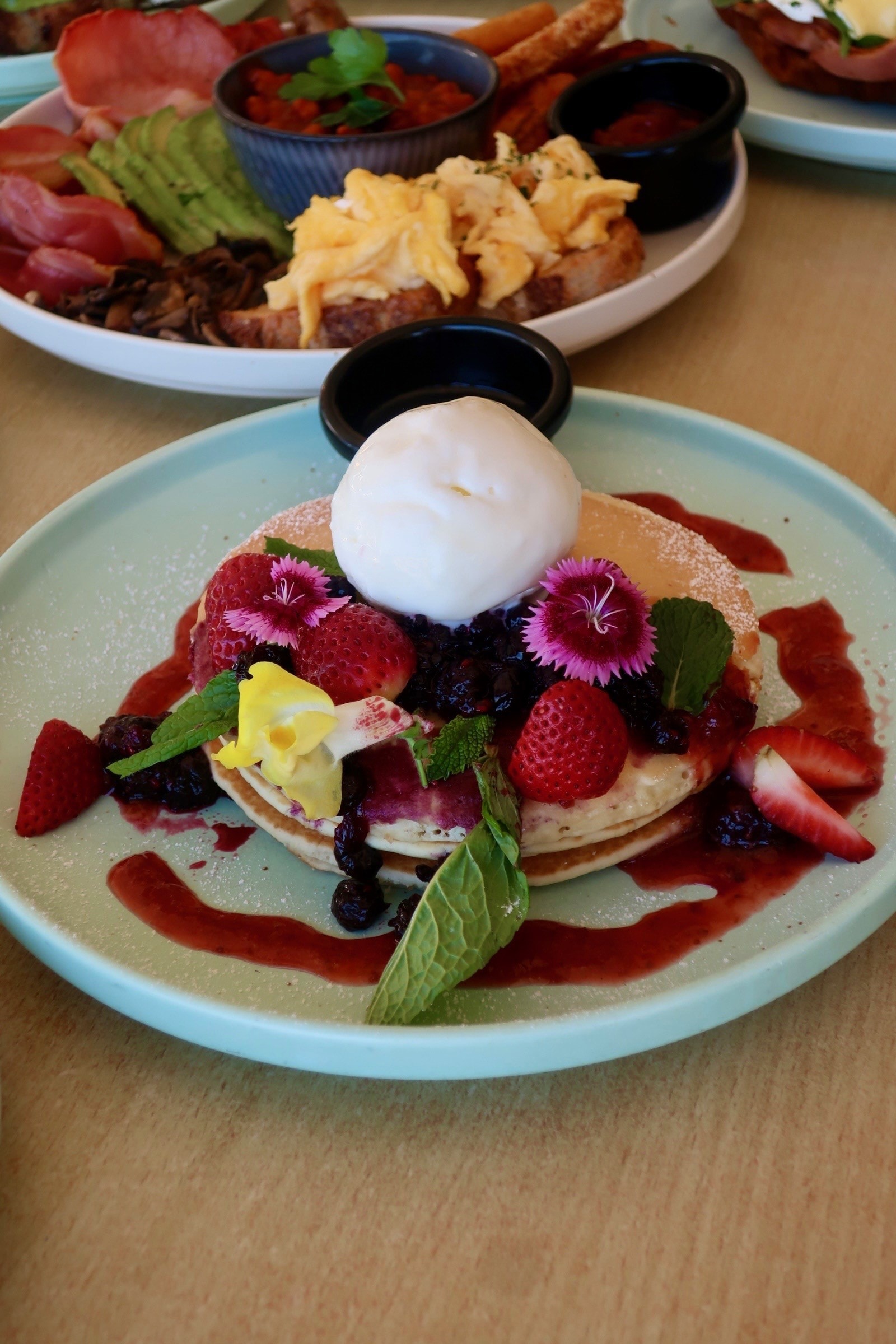 Fluffy pancakes with mixed berries, edible flowers and ice cream