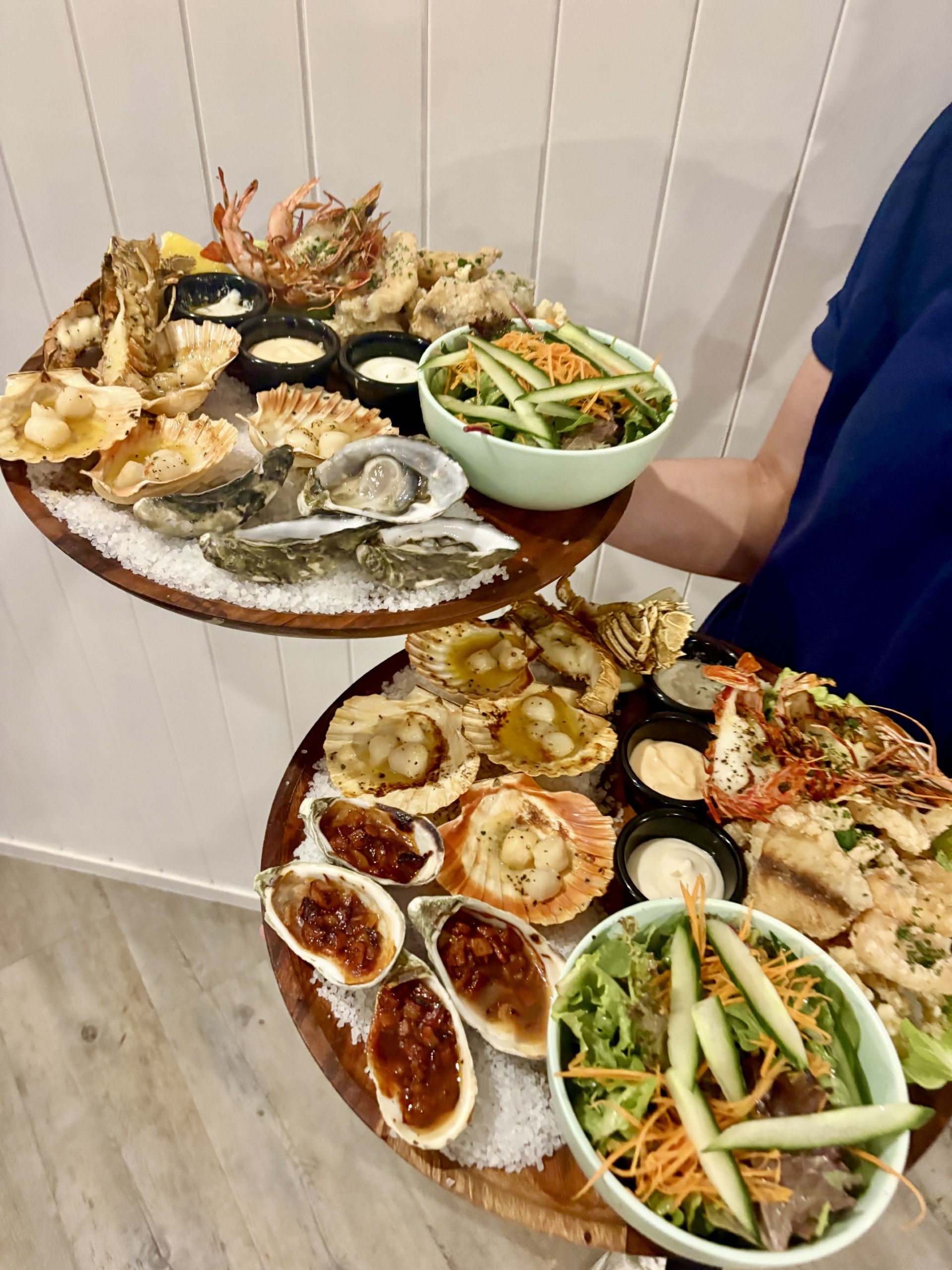 Tiered seafood platter with oysters, scallops, prawns and fresh salad